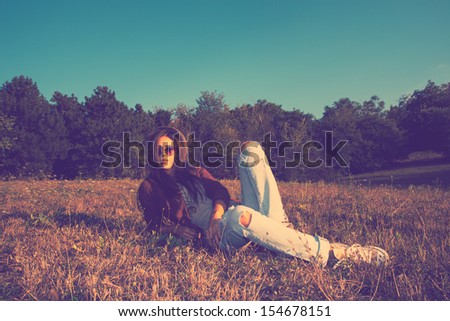 hipster girl on a summer meadow resting in grass retro colors full body shot