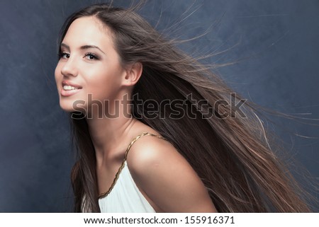 smiling natural beautiful young woman with long fluttering hair studio shot