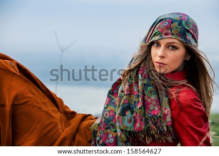 young blond woman in autumn fashion clothes,  red leather jacket, cashmere scarf and brown skirt outdoor shot