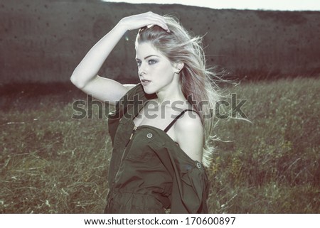 portrait of young  woman in field in green overalls desaturated retro colors