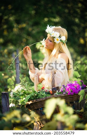 young blonde woman smelling flower and hold basket of  flowers in hand outdoor summer day