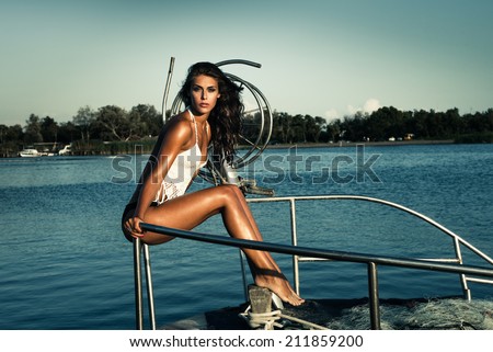beautiful young woman sit on fishing boat at sea full body shot