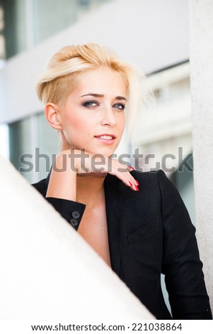 smiling young blue eyes woman with short blonde hair in black blazer outdoor city portrait