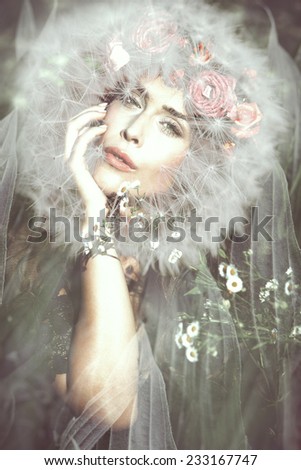 young beautiful  fantasy fairy woman with dandelion around her head on magic meadow