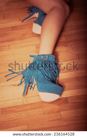 long slim woman legs in blue ankle high heel fringe boot indoor shot on parquet retro colors
