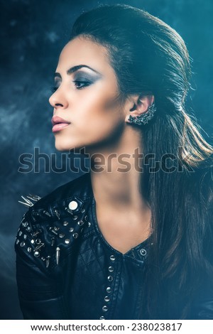 young beautiful woman portrait in black leather jacket with studs, profile, studio shot, dark background