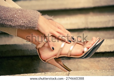 woman legs in high heel golden sandals lean on stairs, outdoor shot, close up