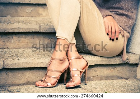 woman legs in high heel golden sandals sit on stairs, outdoor shot