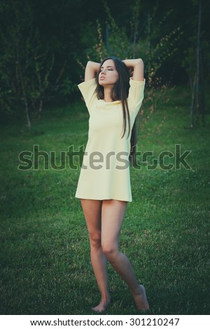 young barefoot woman wearing short retro dress stand barefoot on grass retro colors full body shot