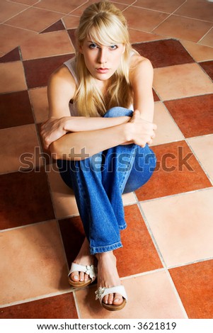 blond woman sitting on a mosaic floor in empty room