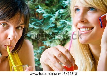 women outside drinking soft drink and talking with cell phone