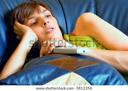 relaxed woman watching tv, lying down on sofa