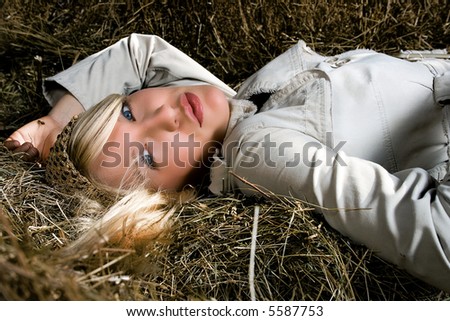 blond woman lying down on haystack