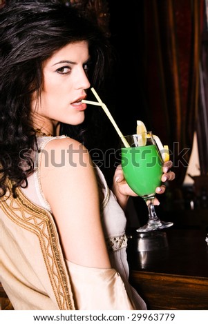black hair woman drinks cocktail in a bar