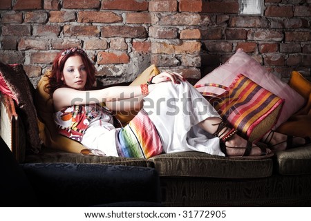 red hair woman in summer clothes resting on sofa