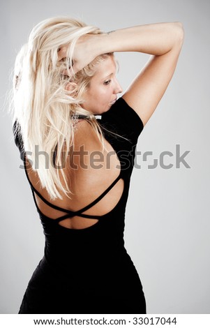 elegant blond woman in black dress,hands in hair,  back view, studio shot