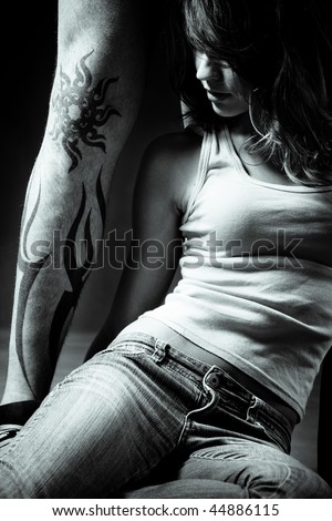 stock photo young woman sitting by man tattoo leg studio shot bw