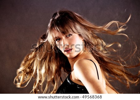 blond young woman with hair in motion, studio shot