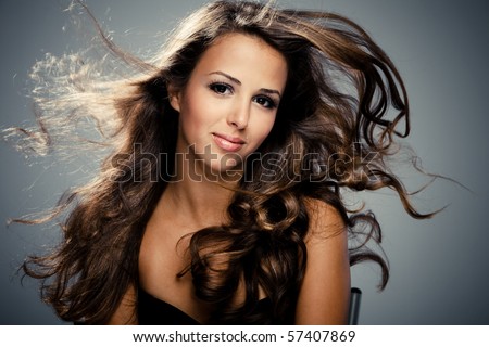 young brunette  woman with long flying hair, studio shot