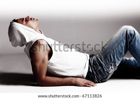 young man in jeans and hood, lie down, profile, studio shot