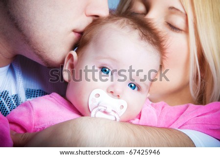 parents kissing their baby girl, studio shot, close up