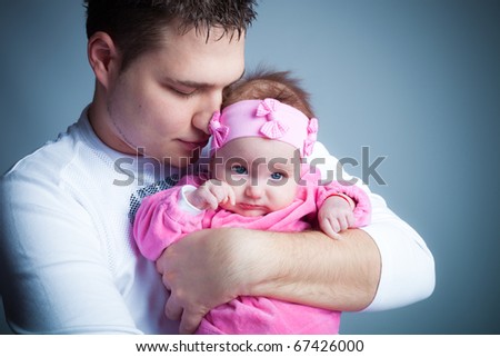 young father hold his baby girl in arms, studio shot