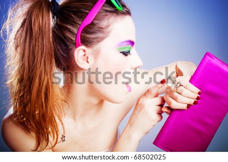 young woman with heavy make up looking at watch  in the form of ring, studio shot