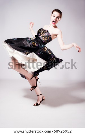 happy young woman dancing in fancy dress, studio shot, full body shot