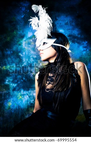 young woman wearing white venetian mask with feathers and black dress, profile, studio shot