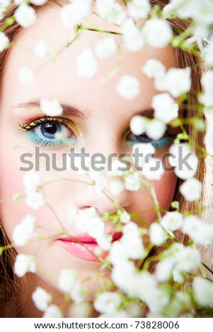 blue eyes woman face behind branch of little white flowers