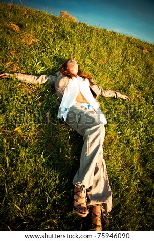 young woman lie in green grass on meadow, summer day sunset