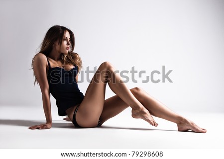 attractive tanned brunette in blue underwear sit on floor, full body shot, small amount of grain added, studio shot