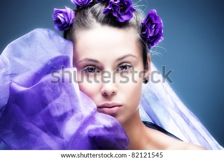 gentle young woman beauty portrait with purple flowers in hair, studio shot