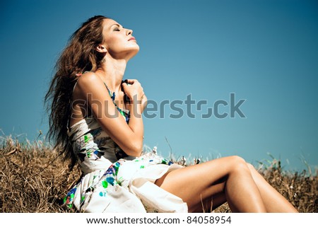 sensual young woman on summer field, blue sky in background, summer day