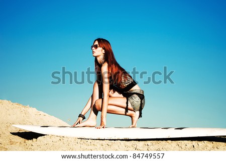 red hair beautiful woman with sunglasses on surfboard in sand, summer day