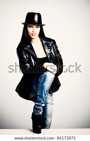 young brunette woman in leather jacket and hat, studio shot, small ammount of grain added