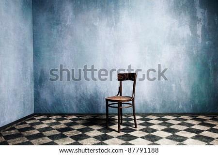 room with old blue walls and tiled floor with wooden chair in the middle