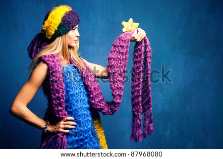 young woman in wool scarfs and flower in hand, studio shot