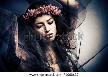 woman in dancing motion  under black veil with wreath of flowers in hair