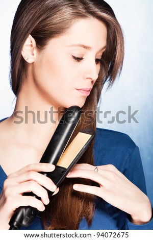 young woman use hair straightener iron, studio shot