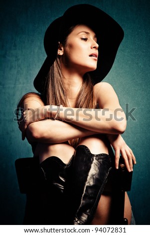young woman portrait with hat, sit on chair, studio shot, small amount of grain added