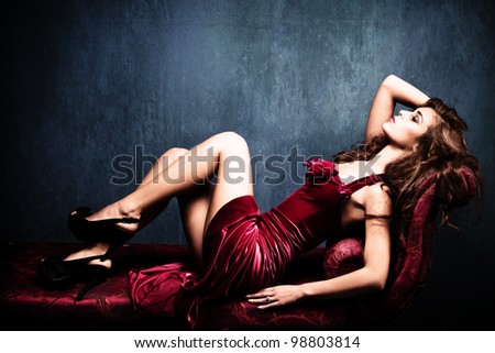 elegant sensual young woman in red dress on recamier indoor shot