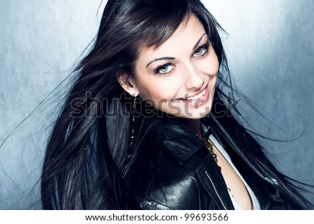 smiling blue eyes young woman with healthy and shiny long hair in black leather jacket, studio shot