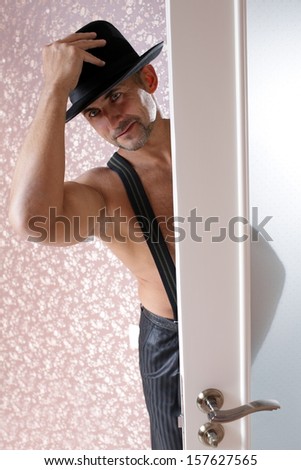 a man in a black hat opens the door and enters the room