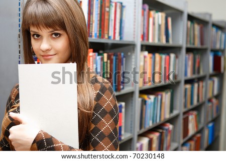 The young nice student reads and considers books on regiments in the big library, smiling in the chamber