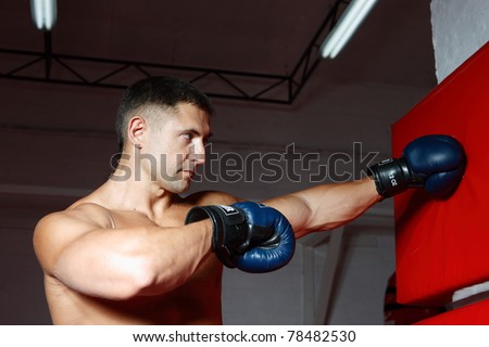 The young guy in the sports form boxes in gloves a pear