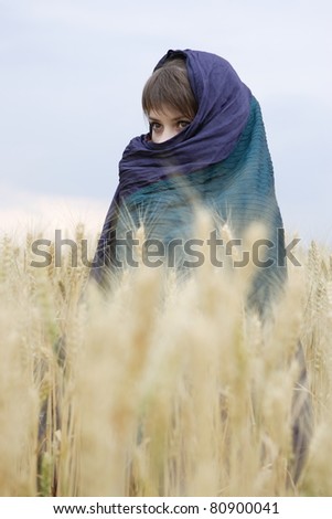 East girl wrapped up in a scarf against the nature looking in a distance