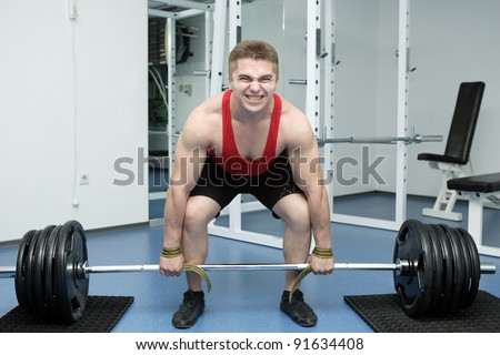 The young sportsman with a well-muscled body lifts dumbbells on a white background