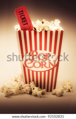 Depiction Of The Fifties Cinema Era With A Vintage Red Striped Old Popcorn Box Overflowing With Buttered Popcorn Coupled With A Movie Ticket