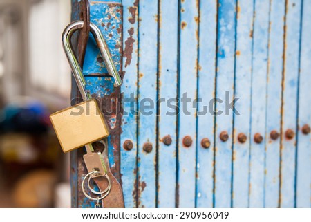 Old open padlock and key with old steel door